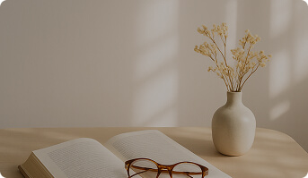An open book with flowers in a vase on the table.